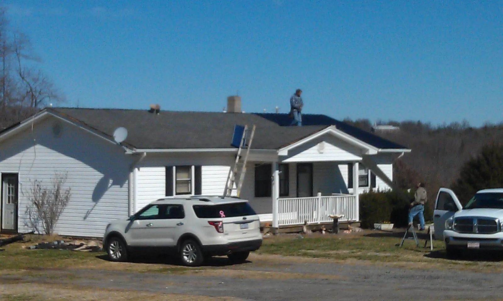 Roofers stripping shingles from a white ranch house roof in Sunbury